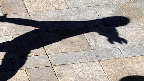 Ein Junge wirft beim Ballspielen einen Schatten auf das Pflaster.