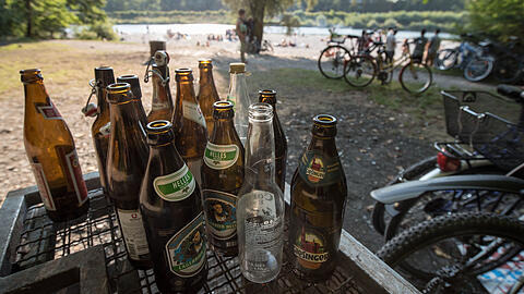 Leere Bierflaschen stehen am Flaucher an der Isar auf einem Abfallcontainer.