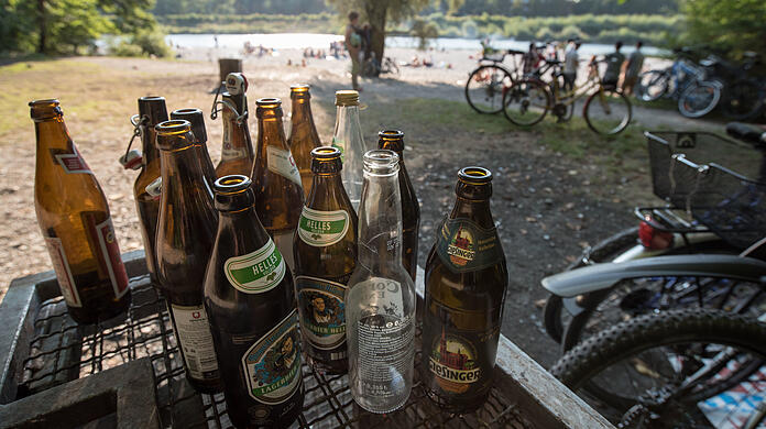 Leere Bierflaschen stehen am Flaucher an der Isar auf einem Abfallcontainer.