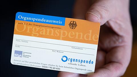 Eine Frau hält einen Organspendeausweis in der Hand.
