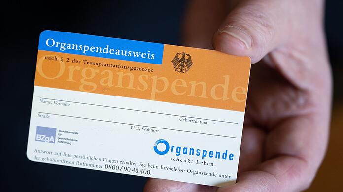 Eine Frau hält einen Organspendeausweis in der Hand.