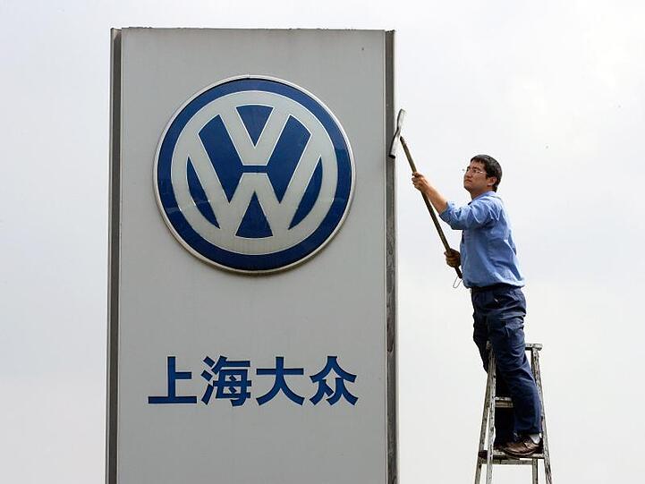 Ein Arbeiter reinigt in der Nähe von Schanghai das Firmenschild eines Volkswagen Autohauses.