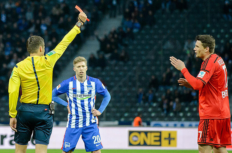 Schiedsrichter Robert Hartmann zeigt Leverkusens Sebastian Boenisch (rechts) nach sdessen Foul am Berliner Yanni Regäsel die rote Karte.