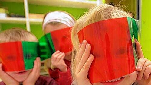 Kleine Forscher: Kinder spielen mit bunten Folien in einer Kita. Kleine Forscher: Kinder spielen mit bunten Folien in einer Kita.