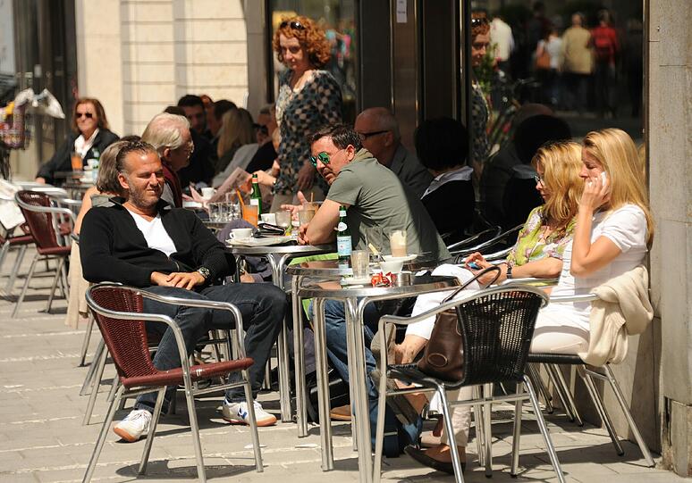 ... dort vor den Cafés saßen sie am Mittwoch in luftigen Klamotten...
