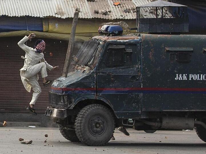 Ein maskierter kaschmirischer Demonstrant springt auf die Motorhaube eines gepanzerten Fahrzeugs der indischen Polizei während einer Demonstration in Srinagar.