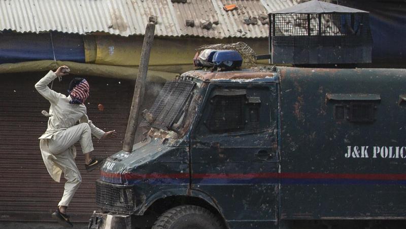 Ein maskierter kaschmirischer Demonstrant springt auf die Motorhaube eines gepanzerten Fahrzeugs der indischen Polizei während einer Demonstration in Srinagar. Ein maskierter kaschmirischer Demonstrant springt auf die Motorhaube eines gepanzerten Fahrzeugs der indischen Polizei während einer Demonstration in Srinagar.