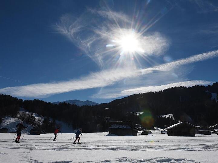 Sportler sind bei Sonnenschein auf der Langlaufloipe in Garmisch-Partenkirchen unterwegs. Foto: Angelika Warmuth