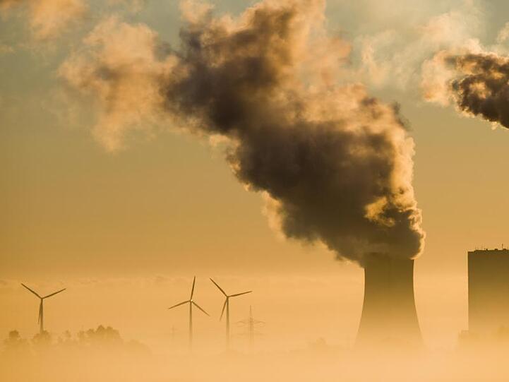 Vergangenheit und Zukunft: Windräder drehen sich hinter einem Kohlekraftwerk.