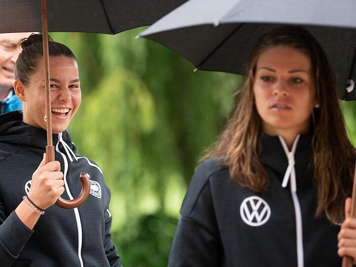 Lena Oberdorf (l) und Melanie Leupolz (r) kommen mit Regenschirm zur Pressekonferenz.