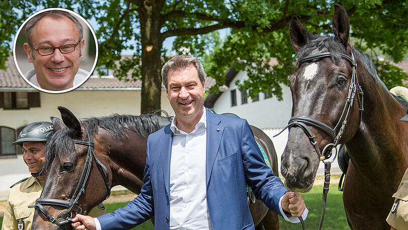 Markus Söder hält beim Pressetermin der Reiterstaffel des Polizeipräsidiums München das Zaumzeug zweier Polizeipferde.