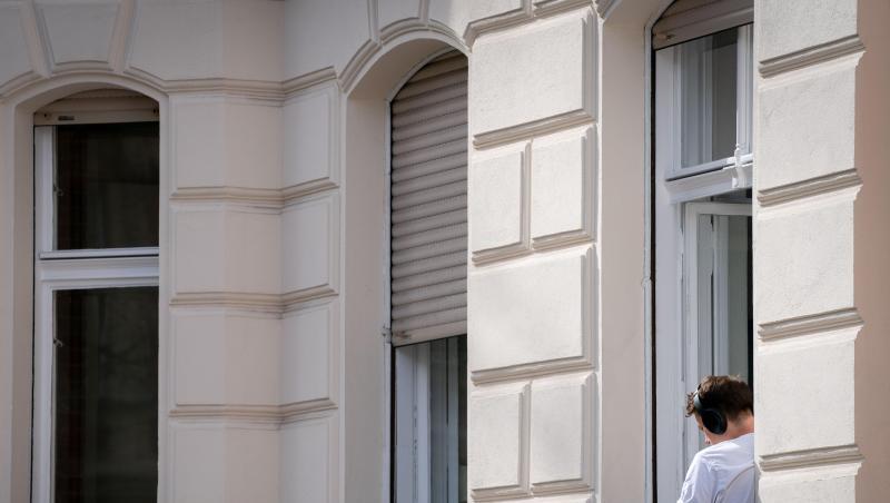 Ein Mann hat sein Homeoffice auf die sonnige Fensterbank seiner Wohnung in Berlin verlegt. Ein Mann hat sein Homeoffice auf die sonnige Fensterbank seiner Wohnung in Berlin verlegt.