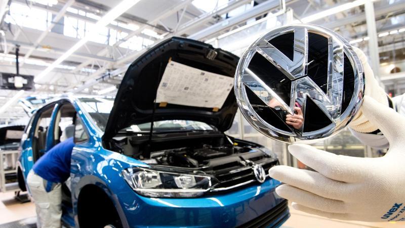 Ein Mitarbeiter zeigt ein VW Logo kurz vor Einbau in einen Volkswagen Touran in der Endmontage im VW Werk. Ein Mitarbeiter zeigt ein VW Logo kurz vor Einbau in einen Volkswagen Touran in der Endmontage im VW Werk.