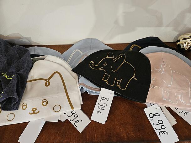 Auch Textilien, wie Kindermützen, Shirts oder Stofftaschen sind zu haben.