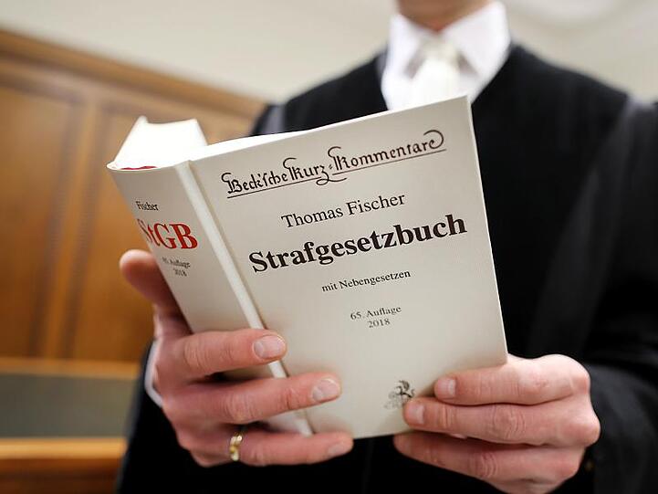 Ein Richter im Gerichtssaal hält das Strafgesetzbuch (StGB) in der Hand. Foto: Oliver Berg/Archivbild