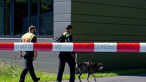Polizeibeamte ermitteln mit einem Spürhund am Schulzentrum in Lohr am Main, wo der tote 14-Jährige gefunden wurde.
