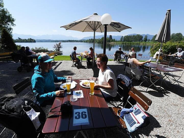 Gäste genießen die Sonne in einem Biergarten am Staffelsee. Foto: Angelika Warmuth/dpa/Archivbild