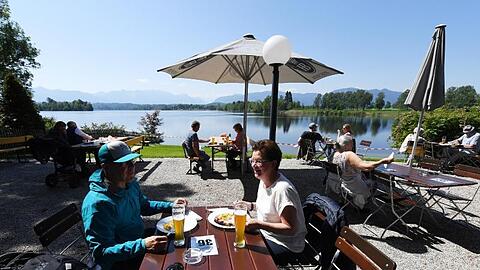 Gäste genießen die Sonne in einem Biergarten am Staffelsee. Foto: Angelika Warmuth/dpa/Archivbild