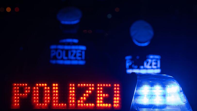 Zwei Polizisten stehen vor einem Streifenwagen.