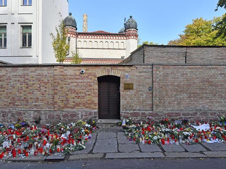Blumen und Kerzen erinnern an der Synagogentür an den Terroranschlag.