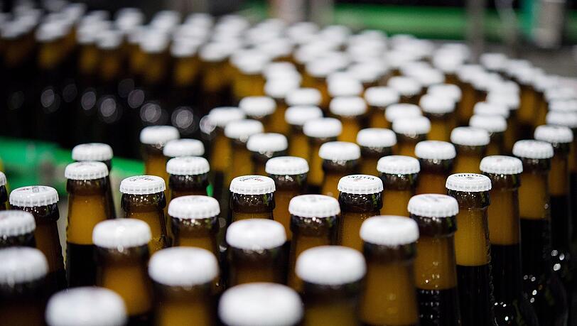 Bierflaschen mit Kronkorken laufen durch die Produktion der Veltins-Brauerei in Meschede-Grevenstein über die Förderbänder einer Befüllungsanlage.