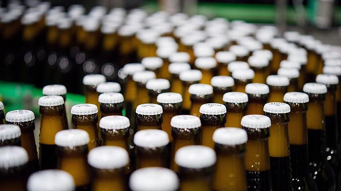 Bierflaschen mit Kronkorken laufen durch die Produktion der Veltins-Brauerei in Meschede-Grevenstein über die Förderbänder einer Befüllungsanlage.
