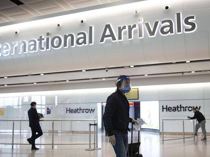 Ein Fluggast mit Mundschutz und Visier geht durch den Flughafen Heathrow.