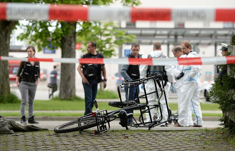Das Fahrrad des verletzten Zeitungsausträgers liegt vor dem Bahnhof in Grafing &ndash; Ermittler der Polizei stehen daneben.