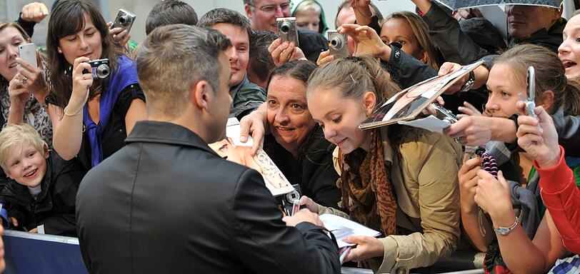 Weltstar im Fan-Gewusel: Robbie Williams verteilte Autogramme vor dem Mathäser-Kino.