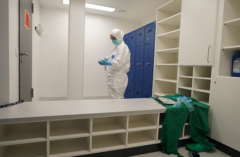 Es herrschen strenge Hygienevorschriften: die Straßenkleidung gegen grüne Laborkleidung tauschen, die Schuhe wechseln, die Hände desinfizieren, zwei Paar Schutzhandschuhe anziehen, Haube und Schutzanzug...