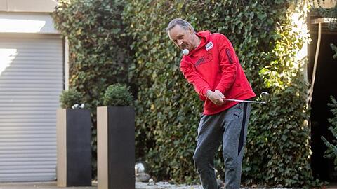 Peter Neururer übt in seinem Garten Golf.