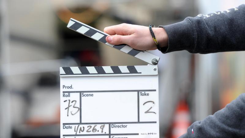 Ein Mann hält eine Filmklappe in der Hand.