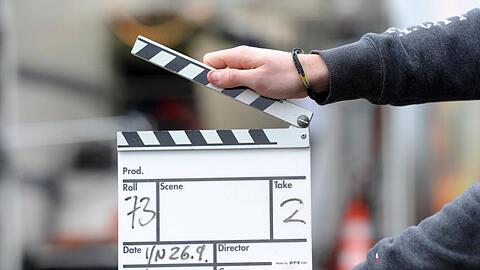 Ein Mann hält eine Filmklappe in der Hand.