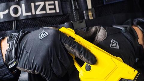 Ein hessischer Polizeibeamter hält einen Taser.