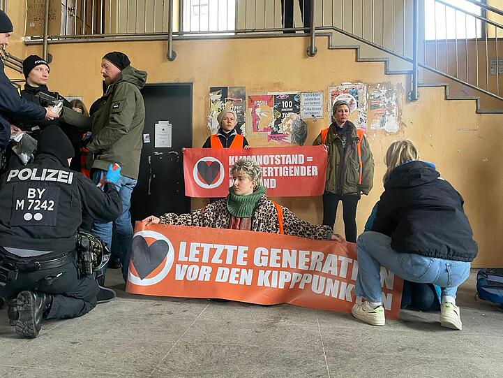 Nachdem die Klima-Aktivistinnen von der Straße getragen worden sind, sitzen sie im Eingang der U-Bahn-Haltestelle "Universität".