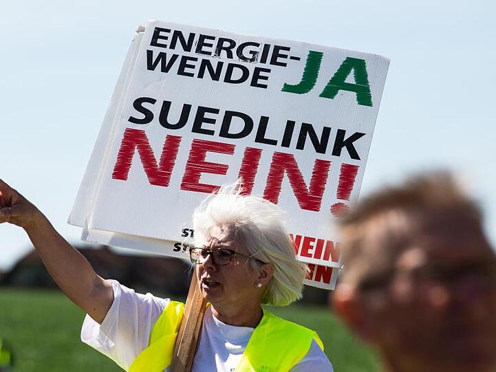 Eine Teilnehmerin hält ein Transparent mit der Aufschrift "Energiewende JA Südlink NEIN". Foto: Swen Pförtner/dpa/Archivbild