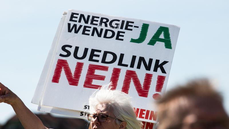 Eine Teilnehmerin hält ein Transparent mit der Aufschrift "Energiewende JA Südlink NEIN". Foto: Swen Pförtner/dpa/Archivbild