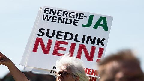 Eine Teilnehmerin hält ein Transparent mit der Aufschrift "Energiewende JA Südlink NEIN". Foto: Swen Pförtner/dpa/Archivbild