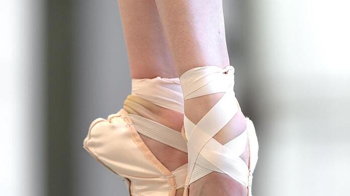 Eine Tänzerin des Bayerischen Staatsballetts steht auf ihren Spitzenschuhen.