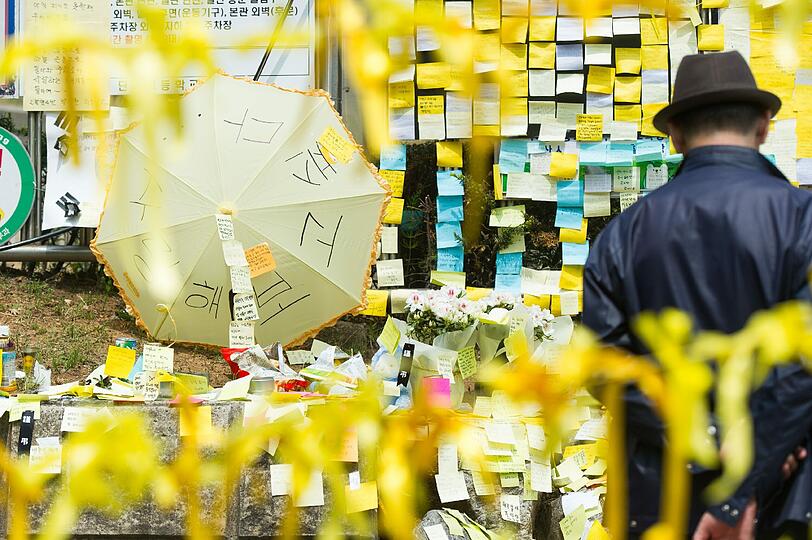 Ein Mann betet vor einer provisorischen Gedenkstätte vor der Danhow High School in Ansan. Diese Schule besuchten die Schulkinder, die seit dem Fährunglück in Südkorea vermisst werden.