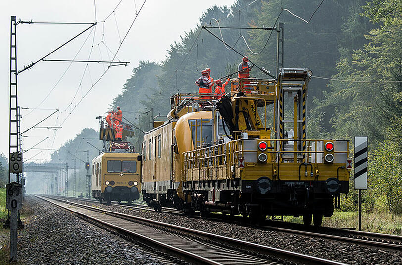 Arbeiter der Bahn reparieren die Oberleitung.
