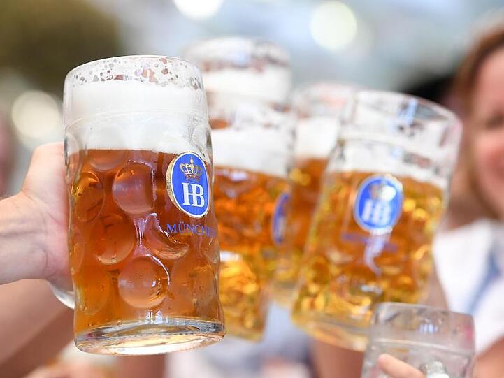 Feiernde stoßen mit ihren Bierkrügen an. Foto: Tobias Hase/dpa-tmn/Symbolbild