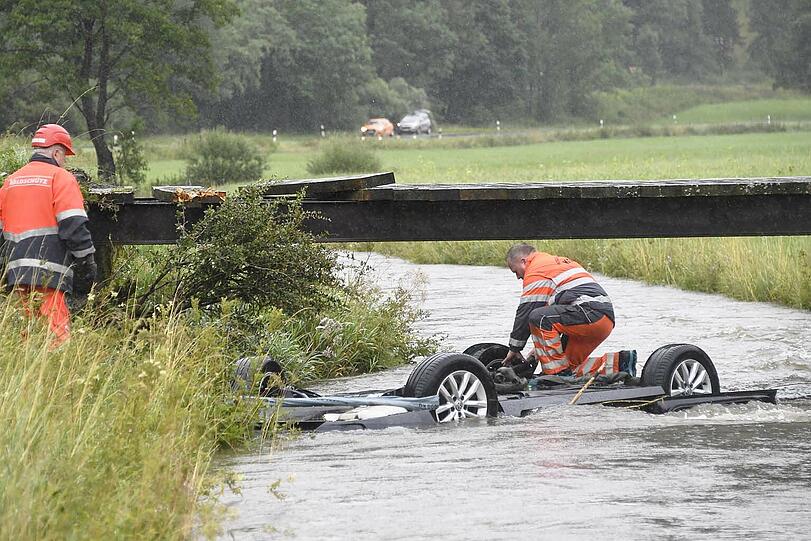 Bei Bayerischzell am Schliersee landet ein Passat kopfüber in einem stark überfluteten Bach. Der Fahrer kann in letzter Sekunde gerettet werden. Die Bilder des Unfalls.