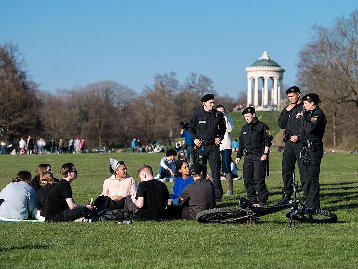 Polizisten reden im Englischen Garten mit einer Gruppe Jugendlicher. Foto: Matthias Balk/dpa/Archivbild
