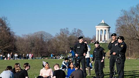 Polizisten reden im Englischen Garten mit einer Gruppe Jugendlicher. Foto: Matthias Balk/dpa/Archivbild