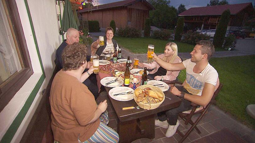 Auch für Martin (29, r.), den charmanten Chiemgauer, und Krankenschwester Julia (26, 2.v.r.) geht die Hofwoche erst los. Neugierig erwartet Martins Familie den Damenbesuch. Schnell ist bei einer ersten gemeinsamen Brotzeit das Eis gebrochen.