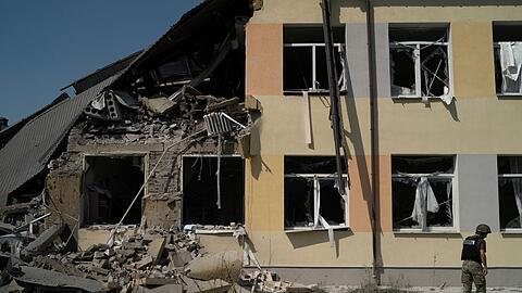 Ein ukrainischer Soldat steht vor einer Schule in der Region Donezk, die bei einem russischen Angriff zerstört wurde.