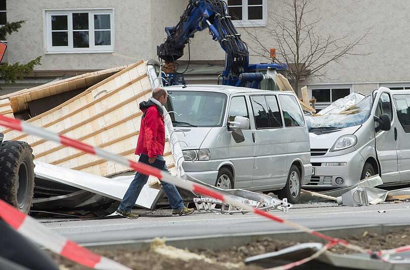 In Weilheim (Oberbayern) geht ein Mann an einem stark beschädigtem Auto vorbei. Ein Teil eines Daches wurde durch das Sturmtief "Niklas" hinweggeweht und beschädigte die Fahrzeuge.