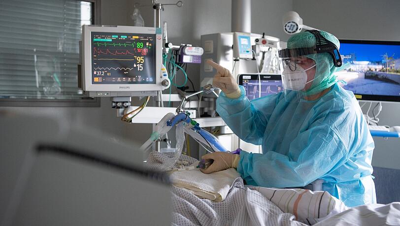 Eine Intensiv-Pflegerin versorgt einen schwer an Corona erkrankten Patienten auf der Intensivstation. Eine Intensiv-Pflegerin versorgt einen schwer an Corona erkrankten Patienten auf der Intensivstation.