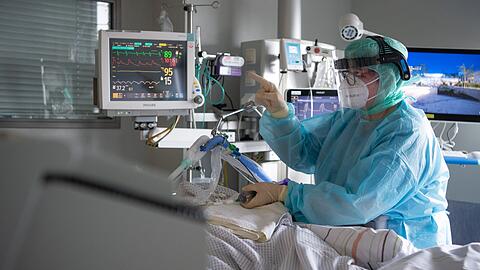 Eine Intensiv-Pflegerin versorgt einen schwer an Corona erkrankten Patienten auf der Intensivstation.